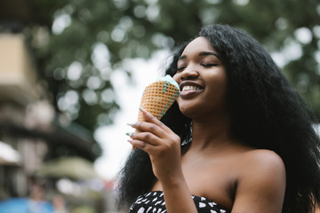 Portrait of a beautiful African american woman eating one ice cream in the street.