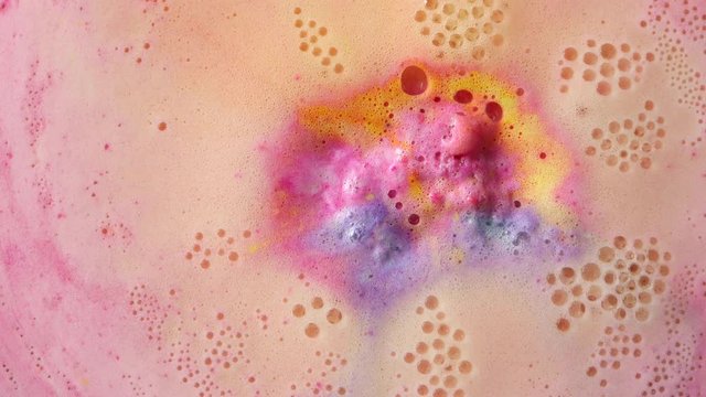 Colorful bathroom bomb dissolves in water. Foam bubbles texture