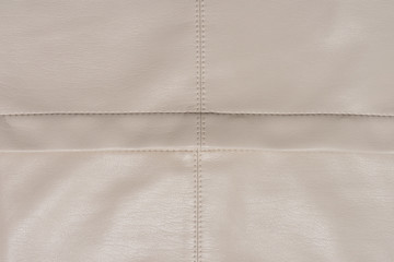 Leather beige surface divided on four even pieces. Abstract background with copy space. A good quality sewing. 