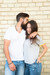 We are just a couple in love with each other. Loving couple hugging on brick wall. Family couple of bearded man and sexy woman. Sensual couple in casual style