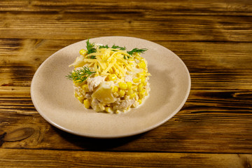 Festive salad with chicken breast, sweet corn, canned pineapple, cheese and mayonnaise on wooden table