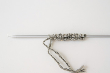 set of hinges on the spokes, the front loop, gray woolen yarn, metal knitting needles on white background