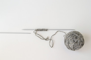 set of hinges on the spokes, the front loop, gray woolen yarn, metal knitting needles on white background