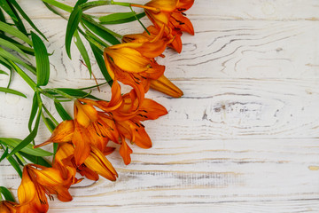 Orange lilies on a white wooden background. Top view, copy space