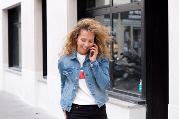 attractive woman walking and talking with cellphone on city street