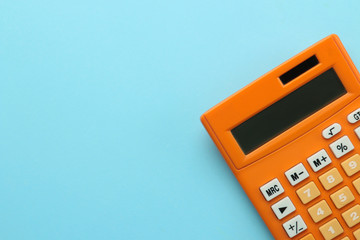 Orange calculator on a bright blue paper background. Office supplies. Education. back to school. top view. place for text. - obrazy, fototapety, plakaty