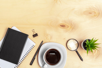 Magnifying glass and notebook on wooden table