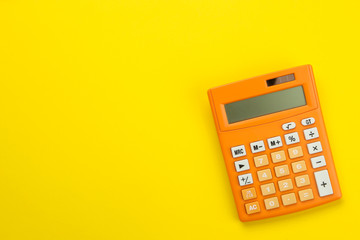 Orange calculator on a bright paper yellow background. Office supplies. Education. back to school. top view. place for text. - obrazy, fototapety, plakaty