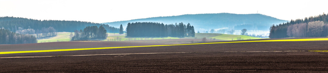 Beautiful panorama of czech meadows with haze in background. Panoramic view of nature in summer. Rolling hills with fog.