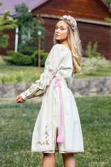 Fototapeta premium Beautiful blonde Ukrainian girl with blue eyes in folk clothing. Boho style in fashion. Traditional and nature style. National look