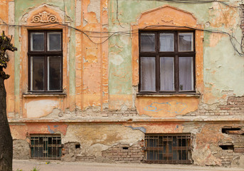 Fototapeta na wymiar Very old, neglected building with old wires and part of tree with chopped branches in city, Ukraine, Chernovtsy