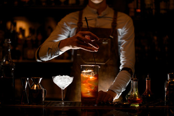 Bartender stirs alcohol cocktail with a spoon