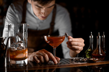 Bartender decorating an alcohol cocktail on bar counter
