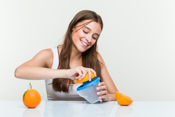 Young caucasian woman holding an orange juicer