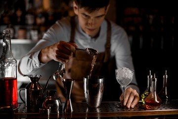 Bartender pours alcohol with spoon and shaker