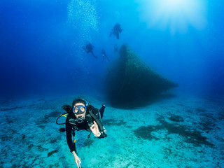 Scuba Taucherin vor einem gesunkenen Wrack gibt das OK Signal im tiefen, blauen Ozean