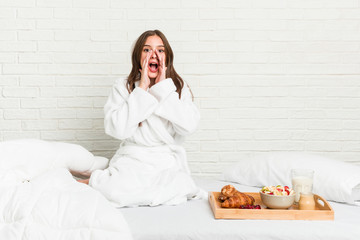 Young caucasian woman on the bed shouting excited to front.