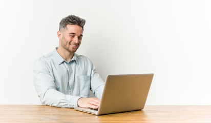 Young handsome man working with his laptop smiling confident with crossed arms.