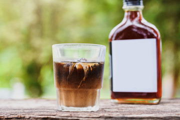 Cold brew coffee with milk on a table outside with cold-brew coffee in a glass bottle for take away