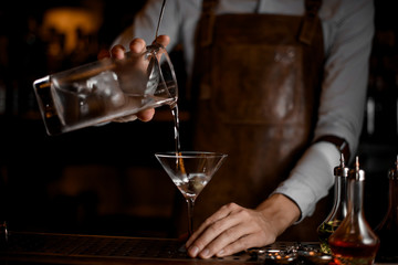 Bartender pours an alcohol drink from jar