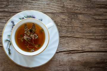 Cup of tea with thyme on wooden background with copy space