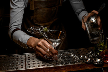 Bartender pouring a martini cocktail from the jar