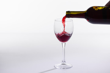 Red wine bottle pour glass on white background with copy space