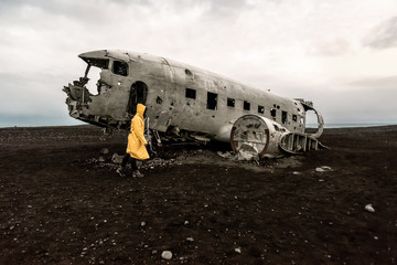 girl in raincoat near remains of the broken plane