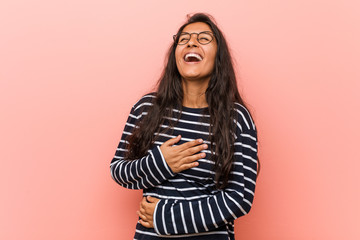Young intellectual indian woman laughs happily and has fun keeping hands on stomach.