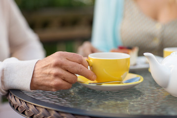 Fototapeta na wymiar old age and people concept - close up of hand of senior woman drinking tea at outdoor cafe