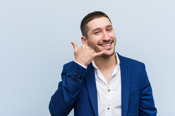 Young business caucasian man showing a mobile phone call gesture with fingers.