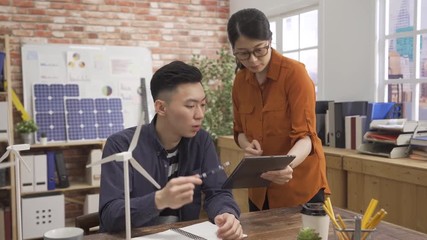 Design creative team meeting discussion working concept. asian elegant woman interior engineer holding digital pad walk close man colleague asking for suggestion advice of green building project.