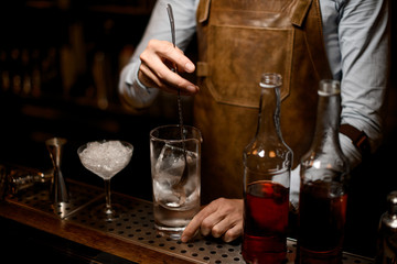 Bartender stirring alcohol cocktail with special spoon
