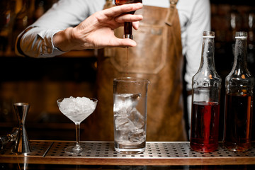 Bartender pours cocktail using vial with dropper