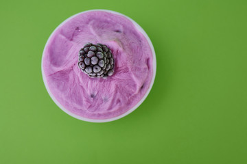  Natural frozen pink yogurt with blackberries and blueberries on a plain background.