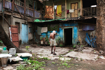 Old man walking outside old building in Wadas of Pune, India