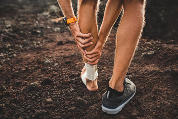 Male runner holding injured calf muscle close-up and suffering with pain. Leg injury. Compression...