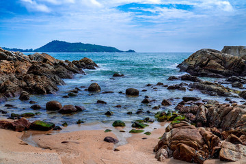 Landscape of stones lined up on the blue sea beach with blue sky background