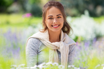 gardening and people concept - happy young woman with flowers at summer garden