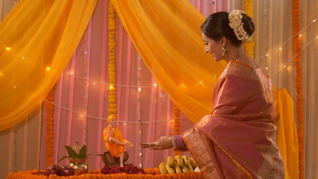 Young Indian woman in sari performing aarti of Lord Sai Baba - Festival concept. Temple in an Indian home. Royalty free video of an attractive lady in traditional clothes performing Hindu rituals a...
