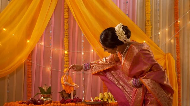 Charming and smiling Indian woman in traditional dress putting tilak on sai baba idol (Sai Pujan). Stock video of a beautiful young woman wearing traditional saree and worshiping Sai baba on Guru P...