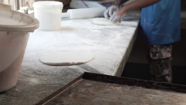 Two persons preparing round flat dough with hand and flour (tagga och d&ouml;pa som pizza f&ouml;r ser ut s&aring;)