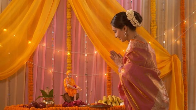 Beautiful Indian woman in saree smiling and offering flowers to Sai Baba during the festival - Guru Purnima. Indian stock footage of a young pretty lady turning against the camera - dressed in sare...