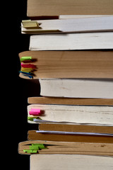 Stack of books with bookmarks on a dark background.Copy space for text.