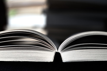 A pile, a pack of books and one book is opened, the ends of the books are background. Copy space for text.