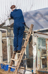 A man in the country repairing a greenhouse
