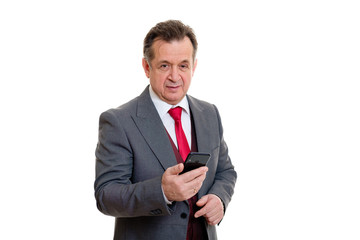 Portrait of handsome confident caucasian mature businessman 55-60 years old in grey tuxedo and red vest. Senior man write or read sms on smartphone and looking to camera on isolated white background