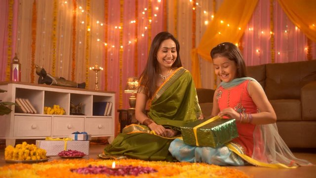 Festival Celebration - A cute girl opening the festival gift with her mom. Happy and Excited. Indian Stock Footage of young mother and daughter wearing Indian dress on the festival