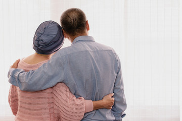 senior couple holding together with hands showing love and concern when wife wearing headscraf...