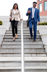 Businessman And Businesswoman Commuting To Work Walking Down Steps Outside Office Building